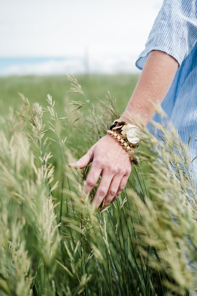 Man running hand along grass as he walks